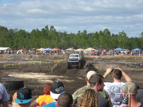 1994 Ford Bronco - A modified truck navigates a muddy course with spectators observing the event.
