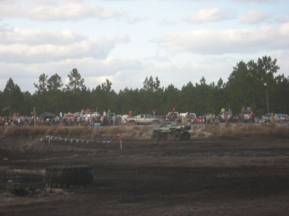 mud bogging event with crowd watching monster trucks and other vehicles