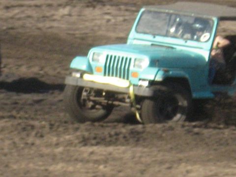 1994 Ford Bronco - A blue Jeep Wrangler is seen from the front, with a yellow strap attached to its bumper.