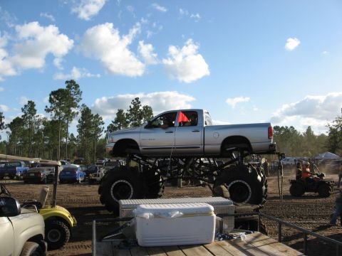 1994 Ford Bronco - Monster truck with large tires and lifted body sits on display at an outdoor event.