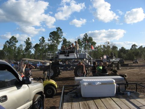 1994 Ford Bronco - A group of people ride atop a large monster truck at an outdoor event, with several other vehicles and a golf cart visible in the backgroun…