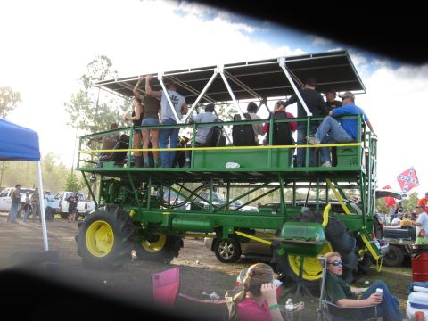 1994 Ford Bronco - A large, custom-built tractor serves as a mobile party platform for a group of people at an outdoor event.