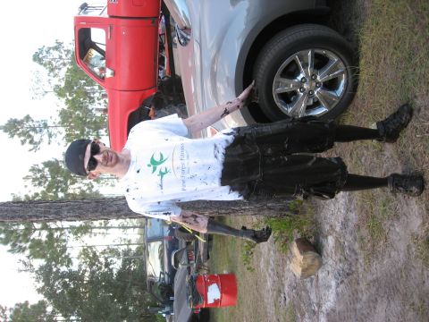 1994 Ford Bronco - A man is covered in mud, standing next to a red truck and a silver SUV in an outdoor setting.