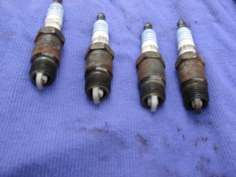 1994 Ford Bronco - Four used spark plugs are shown on a blue cloth, indicating a need for replacement.