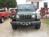 1995 Ford Bronco - A green Jeep Wrangler JK is parked in front of a house, with a red pickup truck to its left.