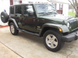 1995 Ford Bronco - Dark green Jeep Wrangler parked on a driveway.