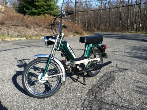 1981 Garelli Rally Sport - A green moped with chrome fenders and handlebars is parked on a cracked asphalt road.