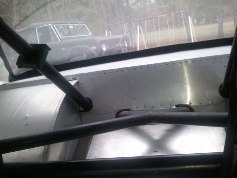 1967 Ford Mustang - A dark Ford Bronco is visible through the interior roll cage and windows of another vehicle.