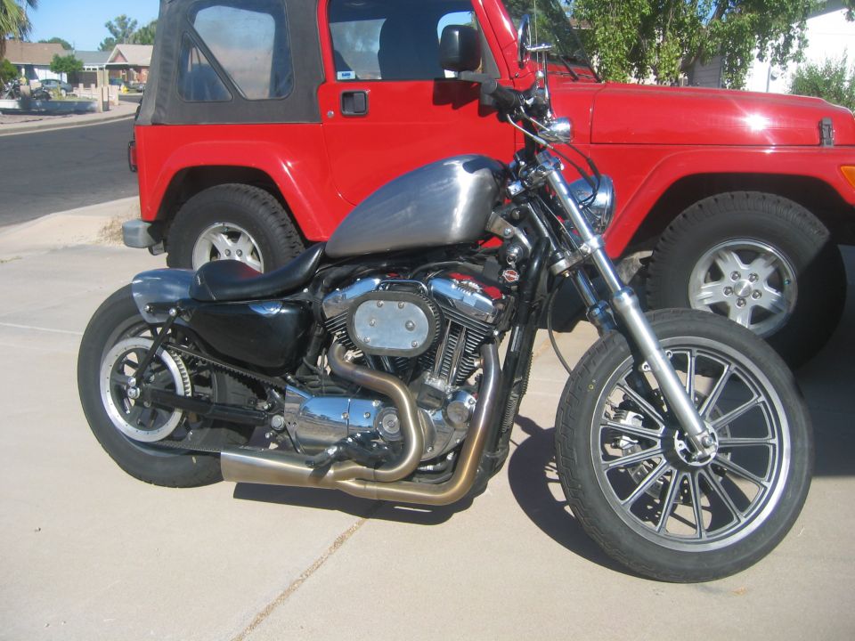 Silver 2006 Harley-Davidson Sportster parked next to red Jeep