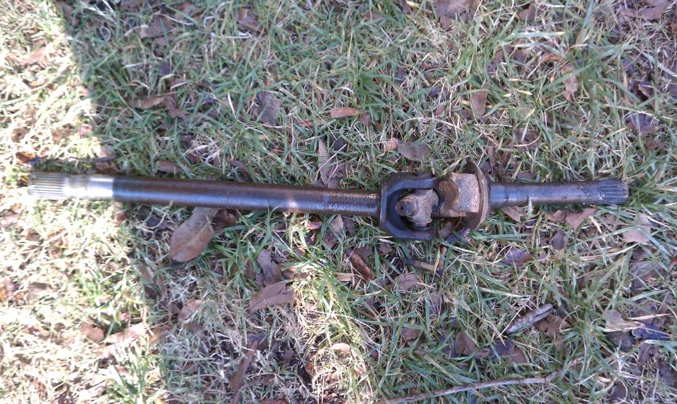 Driveshaft with U-joint lying on grass. Has splines on both ends