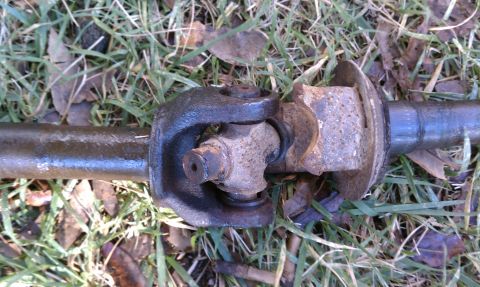 1979 Ford Bronco - A close-up view of a worn driveshaft universal joint resting on the ground.