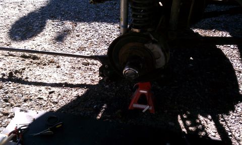 1979 Ford Bronco - Close-up of a vehicle's brake and suspension system, with a jack stand holding it up.