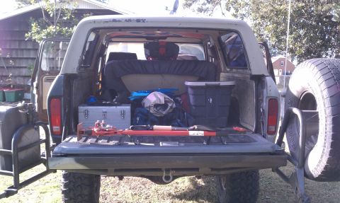 1979 Ford Bronco - The open tailgate of a 1978 Ford Bronco reveals a loaded cargo area with various tools and equipment.