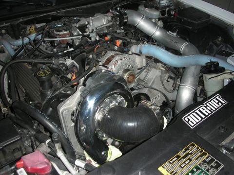 2004 Ford Crown Victoria - Custom supercharger system installed in an engine bay, polished chrome and blue silicone hoses. An ADTR.net sticker is present on the black…