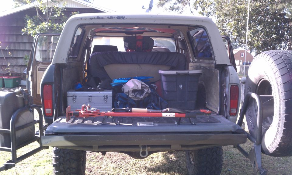 Rear view of a 1978 Ford Bronco with tailgate down, showing tools and gear in the cargo area