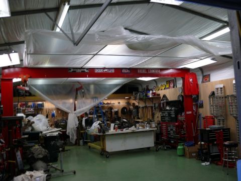 1976 Chevrolet Corvette - A busy garage workshop is equipped with a car lift, extensive tool storage, and a workbench, suggesting ongoing automotive projects.