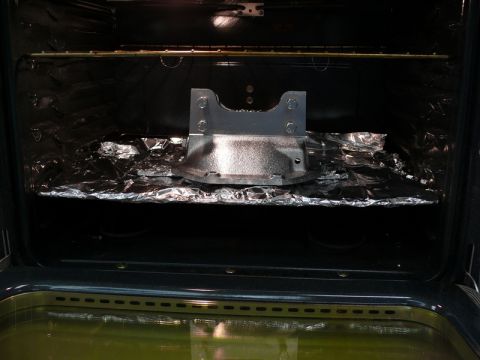 1976 Chevrolet Corvette - A metal part is placed on aluminum foil inside an oven.