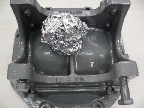 1976 Chevrolet Corvette - A gray metal part, possibly from a GM vehicle, has a crumpled piece of aluminum foil placed on top.