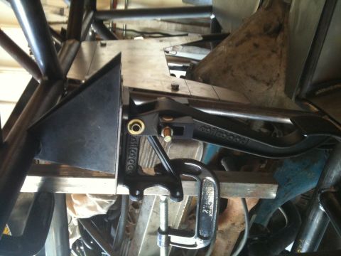 1966 Ford Bronco - Close-up of a brake caliper assembly attached to a metal frame with a clamp.