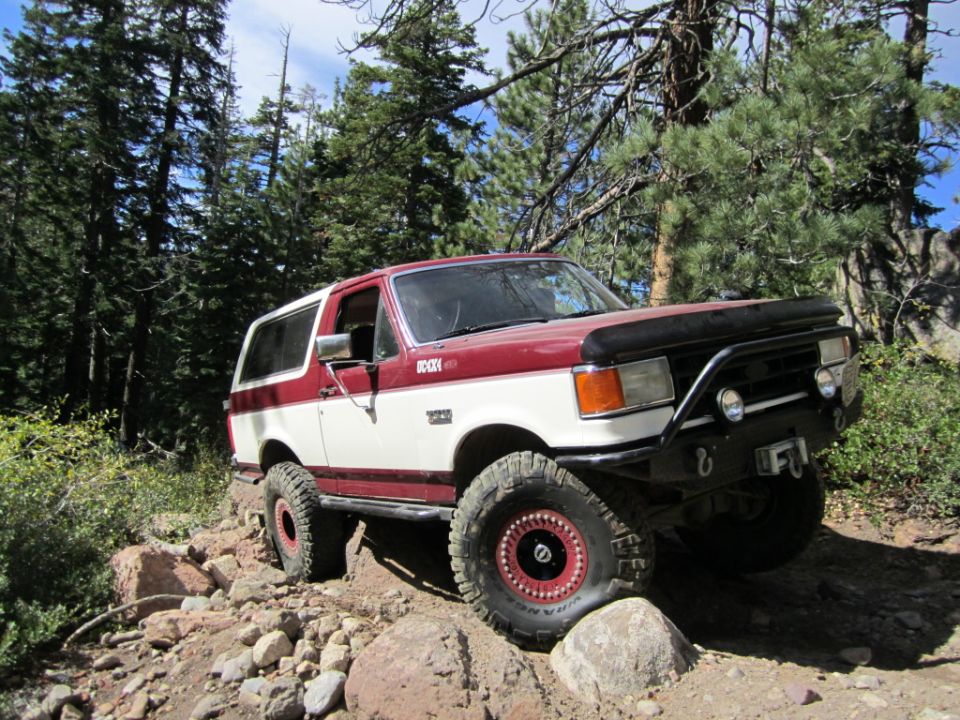 Red and white 1991 Ford Bronco on rocky trail