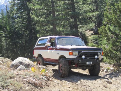 1991 Ford Bronco - A modified Ford Bronco navigates a rocky, wooded trail.
