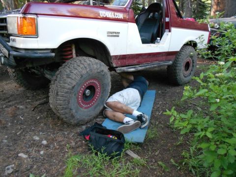 1991 Ford Bronco - Mechanic works on a modified 1991 Ford Bronco in an outdoor setting.