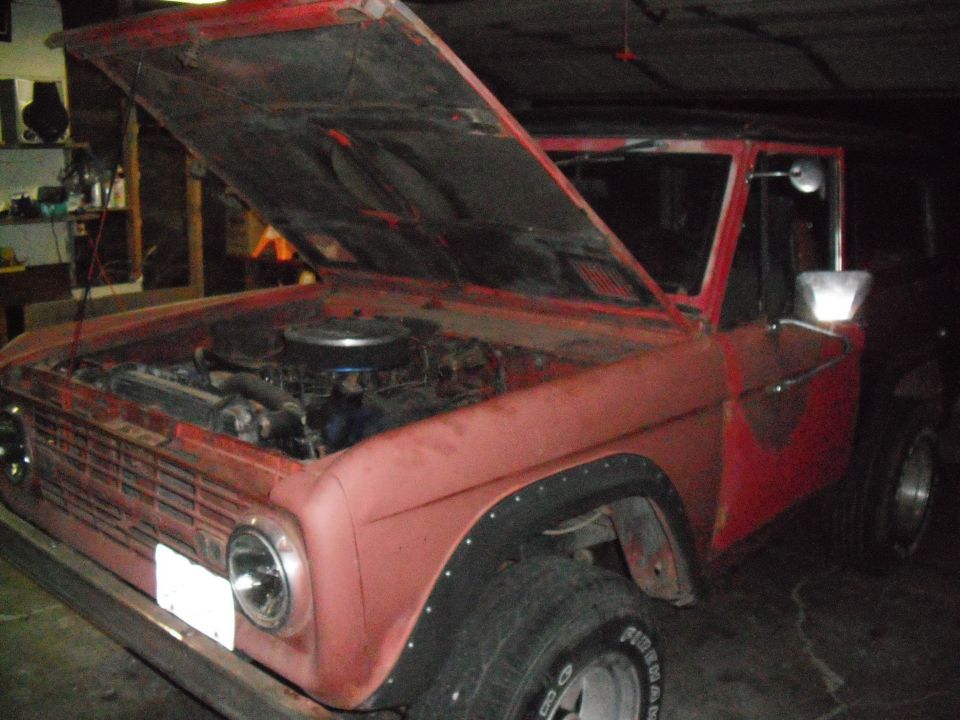 red Ford Bronco, hood open, showing engine bay. Appears to be an older model