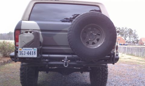 1979 Ford Bronco - This Ford Bronco, seen from the rear, features a spare tire and a jerry can, with camouflage paint and a Virginia license plate.