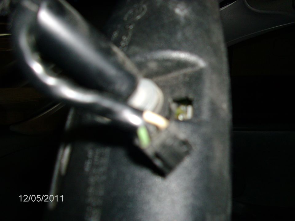 Close-up of a black wiring harness and connector with green and white wires