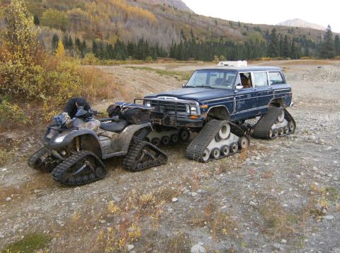 2000 Ford E350 - An ATV and a blue SUV have been fitted with tank treads for off-road travel in a mountainous, wooded area.