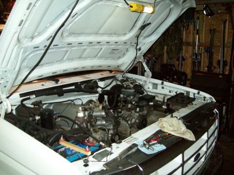1993 Ford F-150 - The engine compartment of a white pickup truck is shown with the hood raised, revealing the engine and various components.