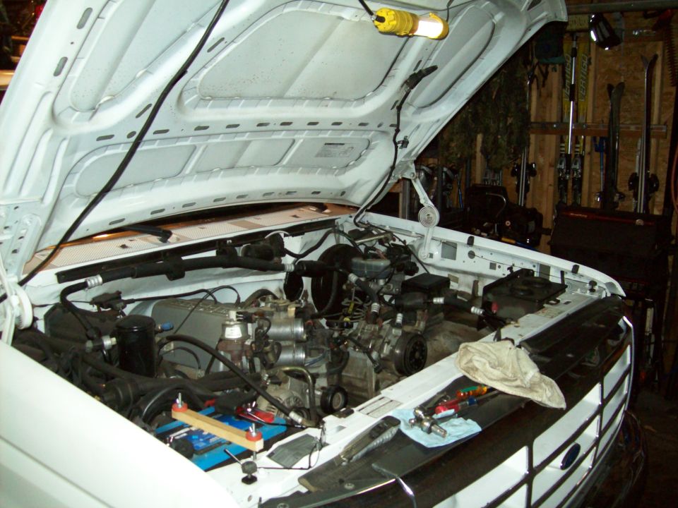 Pickup truck engine bay with hood open. Tools are on the fender