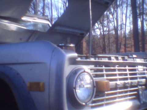 1979 Ford Bronco - Front view of a 1979 Ford Bronco, showing the grille and headlight with the hood raised.