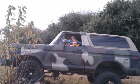1979 Ford Bronco - Children enjoy a ride in a camouflage-painted 1979 Ford Bronco, a classic SUV known for its ruggedness.