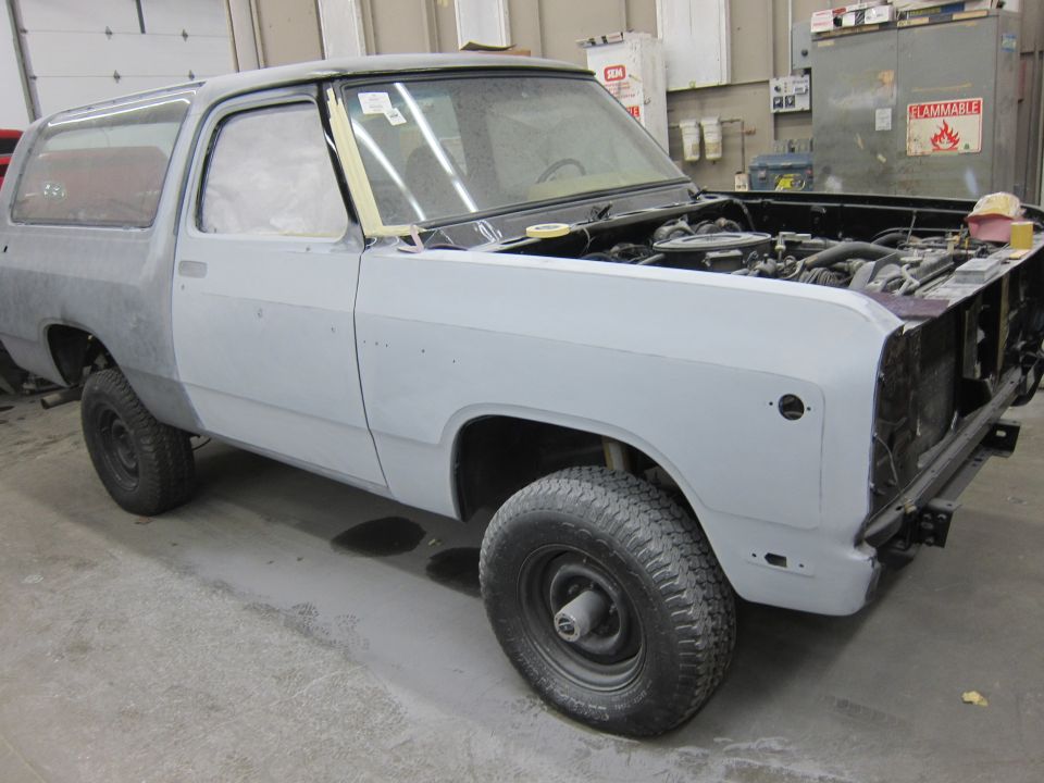 Gray SUV with hood open, undergoing repairs, showing primer on body panels