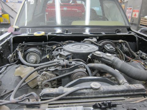 1987 Dodge 1500 - Engine bay of a 1987 Dodge 1500, showing the V8 engine, radiator, and various hoses and wiring.