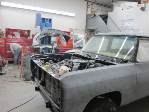 1987 Dodge 1500 - A 1987 Dodge 1500 truck is in a workshop with its hood open, showing the engine and bodywork in primer.