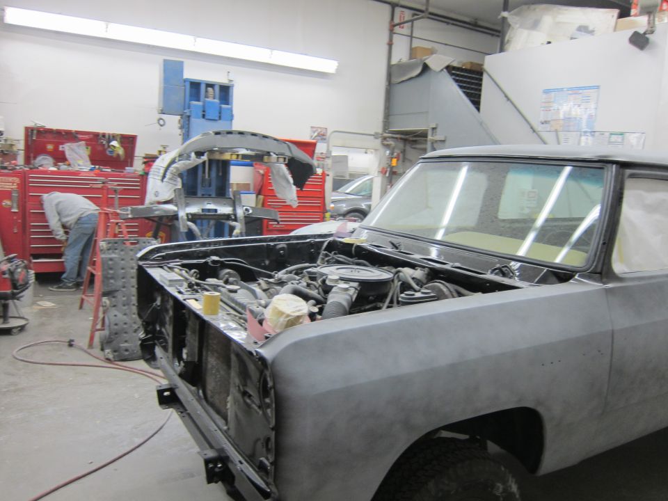 1987 Dodge 1500 truck in a workshop, hood open, engine exposed, body in primer