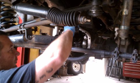 1979 Ford Bronco - Close-up view of vehicle's undercarriage during repair work, showing steering and suspension parts.