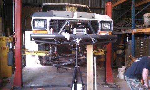1979 Ford Bronco - This Ford truck is undergoing modifications in a workshop, with its front end elevated on a lift.