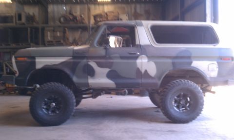 1979 Ford Bronco - This lifted Ford Bronco, painted in a camouflage pattern, is viewed from its side profile inside a garage.