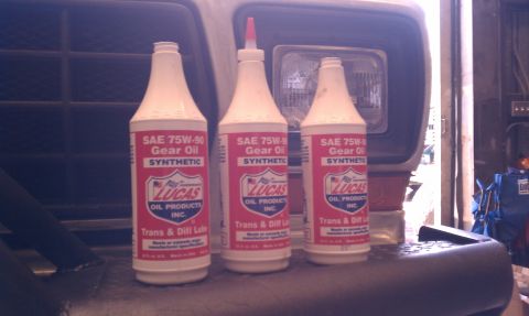 1979 Ford Bronco - Three bottles of Lucas Oil SAE 75W-90 synthetic gear oil are lined up, with a vehicle headlight in the background.