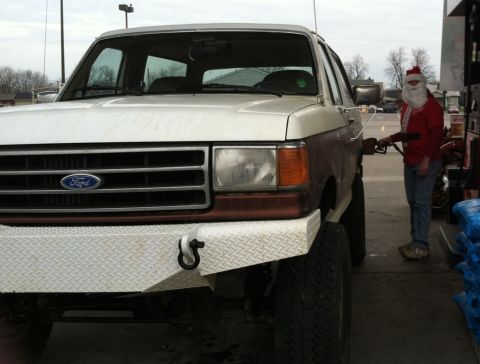 1989 Ford Bronco - A person dressed as Santa Claus fuels a 1989 Ford Bronco at a gas station.
