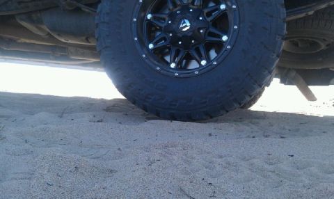2005 Dodge 1500 - Undercarriage view of a truck with aftermarket wheels, resting on sand.