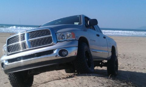 2005 Dodge 1500 - A silver Dodge Ram pickup truck is parked on a beach with the ocean in the background.