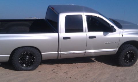 2005 Dodge 1500 - This silver 2005 Dodge 1500 pickup truck is shown from the side, black aftermarket wheels and tinted windows.