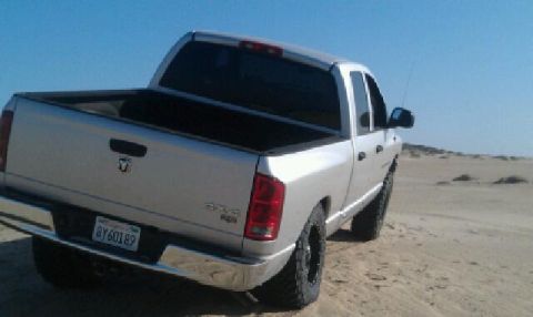 2005 Dodge 1500 - Silver 2005 Dodge 1500 pickup truck on a sandy terrain.
