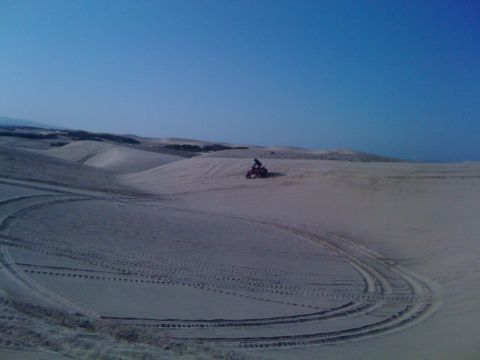 2005 Dodge 1500 - An ATV navigates the sandy terrain of the dunes, leaving tracks behind.