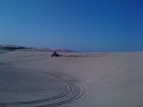 2005 Dodge 1500 - A quad bike kicks up dust as it navigates the sandy terrain of the dunes.