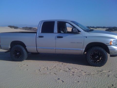 2005 Dodge 1500 - Silver 2005 Dodge 1500 pickup truck with crew cab and aftermarket wheels on sand dunes.